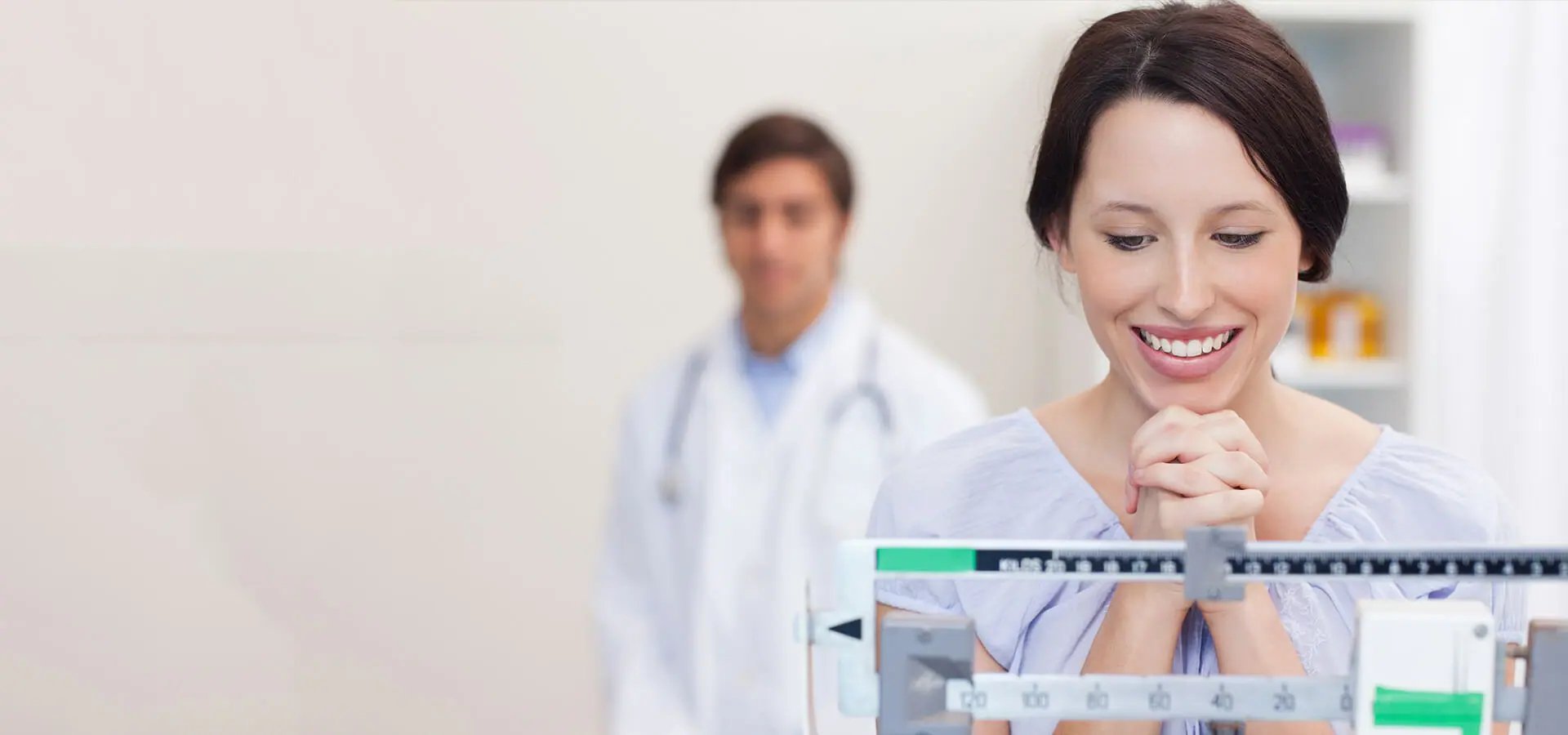 Woman standing on weight scale with doctor in background